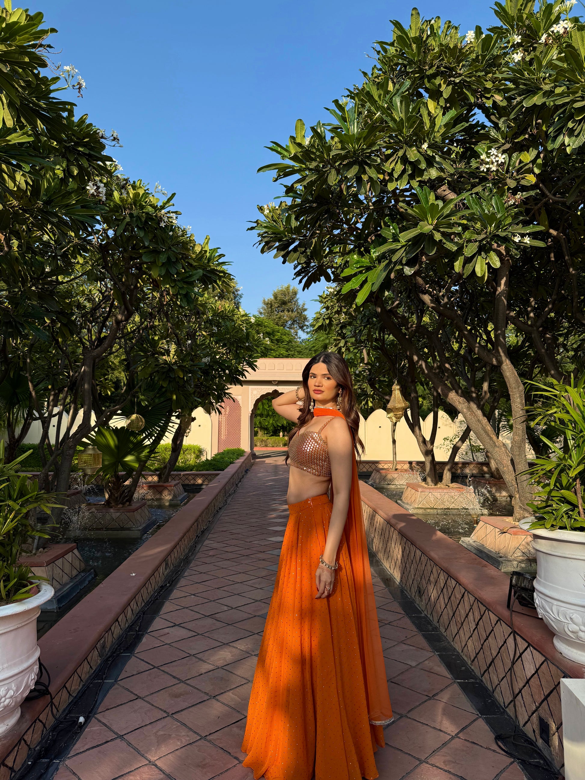 Imagine By Shiwali Chameli Orange Lehnga showcasing intricate embroidery and vibrant orange fabric for festive occasions.