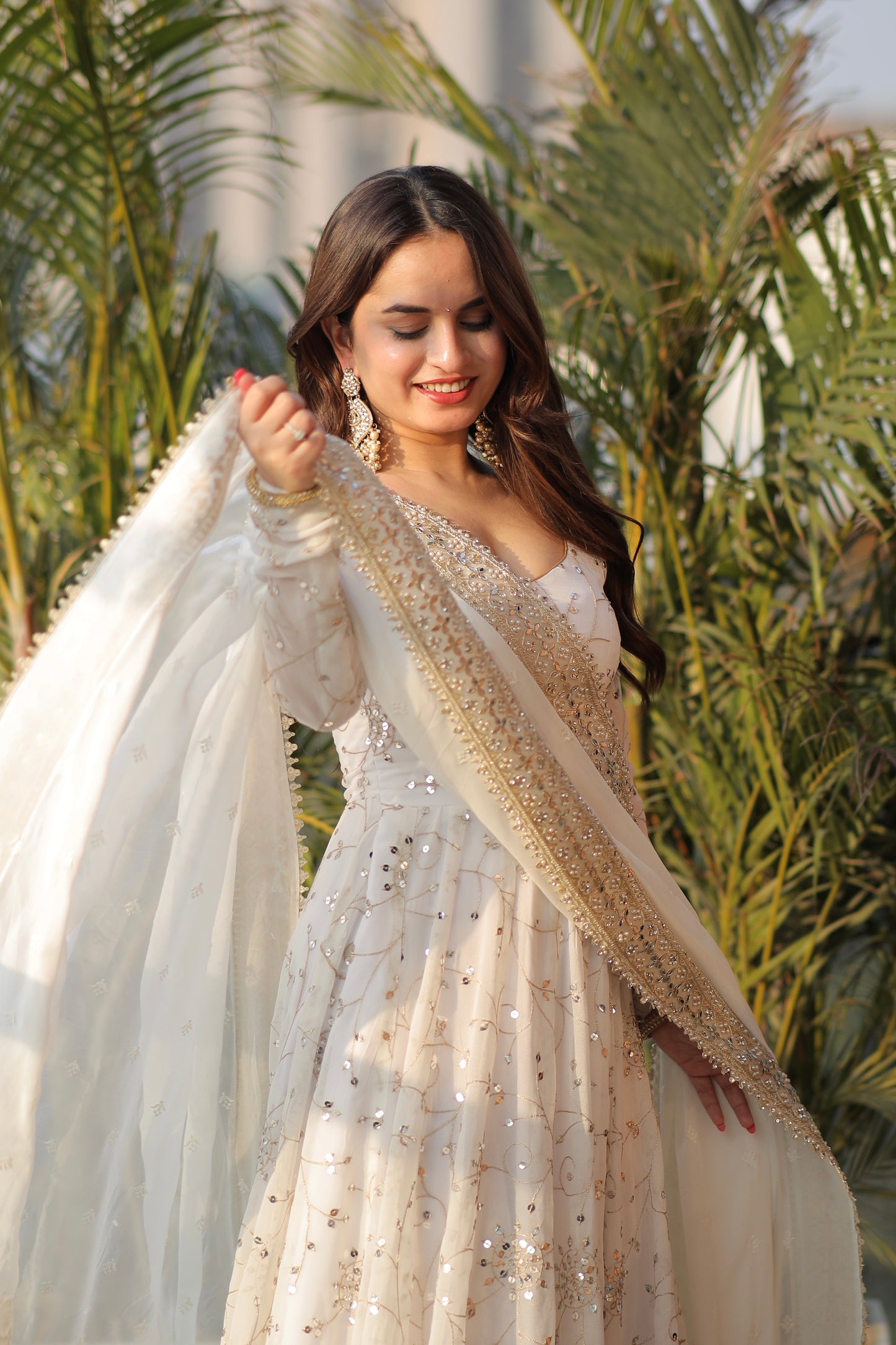 White embellished Maastani Anarkali dress by Imagine By Shiwali with intricate embroidery and flowing fabric, displayed on a hanger.
