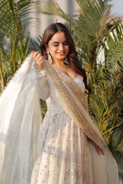 White embellished Maastani Anarkali dress by Imagine By Shiwali with intricate embroidery and flowing fabric, displayed on a hanger.