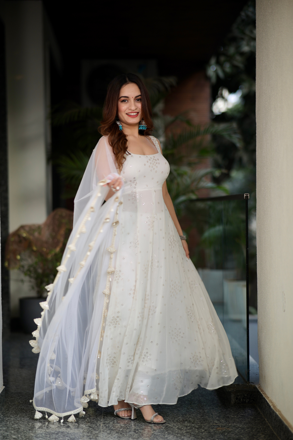 White Dolly Anarkali dress by Imagine By Shiwali featuring intricate embroidery and flowing fabric, displayed on a hanger.